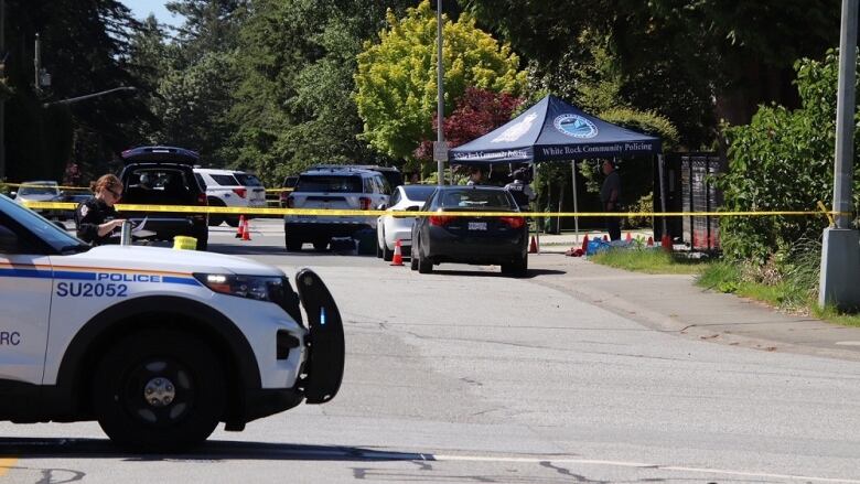 Several RCMP vehicles parked on a street and yellow police tape across the photo. 