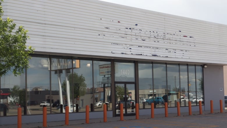 A vacant building with orange bollards in front of it.