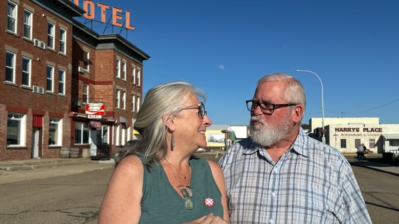 A couple stand together on a small-town main street.