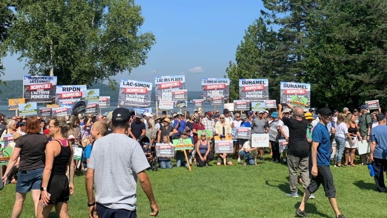 A crowd of people gathered with posters denouncing the La Loutre mining project and mining in the Outaouais region. The rally took place near the Lac-des-Plages municipal beach.