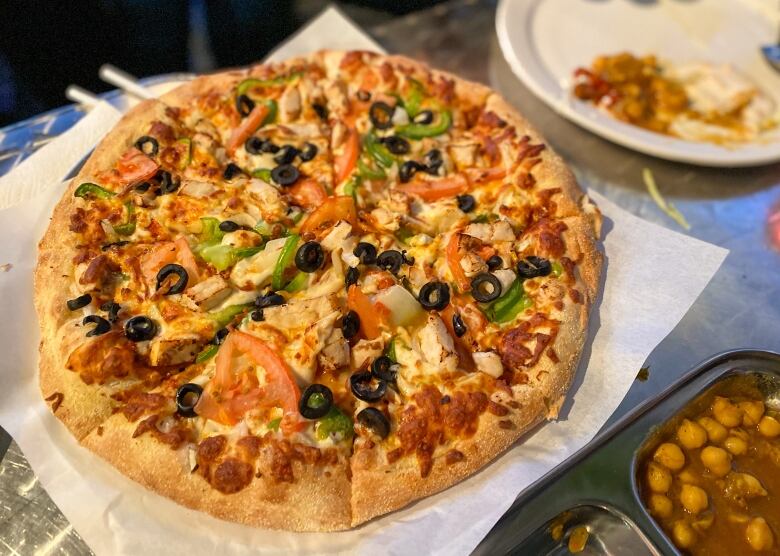 A round pizza surrounded by other foods. 