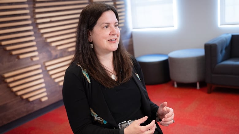 A woman gestures with her hands while seated for an interview.