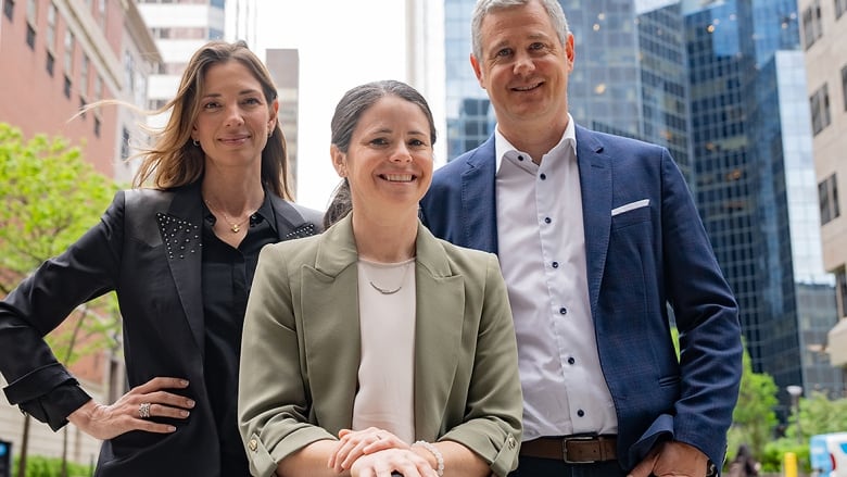 Three Canadian women's soccer executives, including two females and one male dressed in suit jackets, pose on the streets of Montreal on May 27, 2024. 