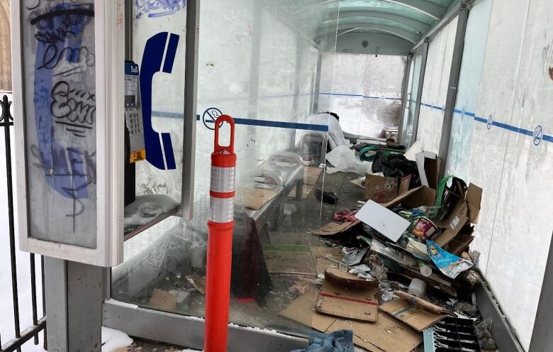 A messy bus shack is seen in winter, the glass frosted.