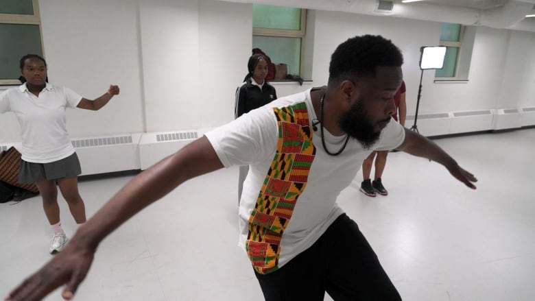 Steev Blackette and his students practicing their stepping routine in a plain white room