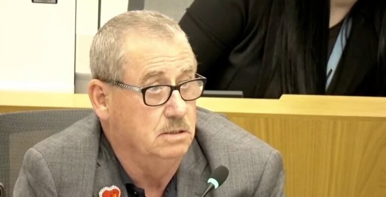 A councillor sits in a council chamber. 