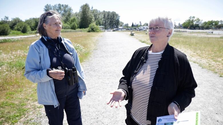 Two women stand on a pathway