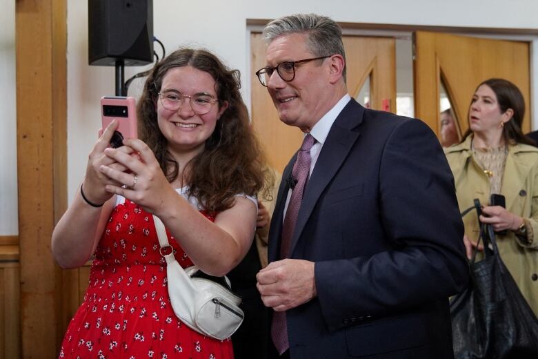 A man in a tie takes a selfie with a supporter.