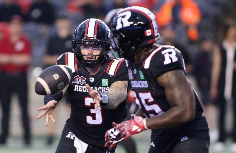 A football player tosses the ball to a teammate with two hands.