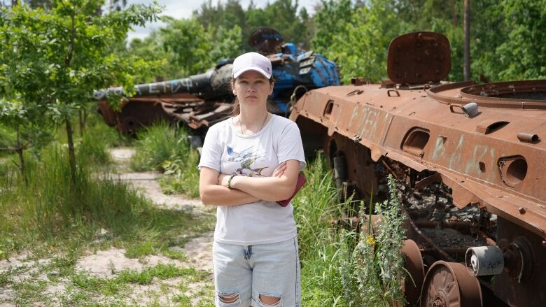 Anastasia Bulba stands in front of rusted Russian military vehicles that have been sitting on the side of the road in Dmytrivka since Ukrainian forces reclaimed this community 30 km west of Kyiv in March of 2022.