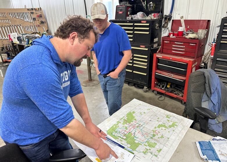 Two men look at a map on a desk in a shop.