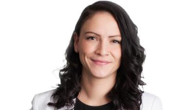 A woman in a white blazer poses for a head shot.