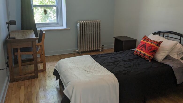 A bedroom with a single bed, a window, a dresser and a desk. 