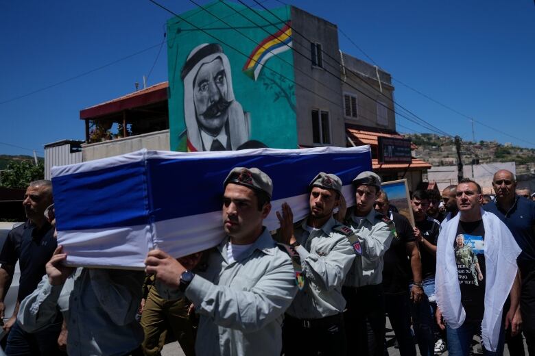 Men carry a casket in a funeral procession.