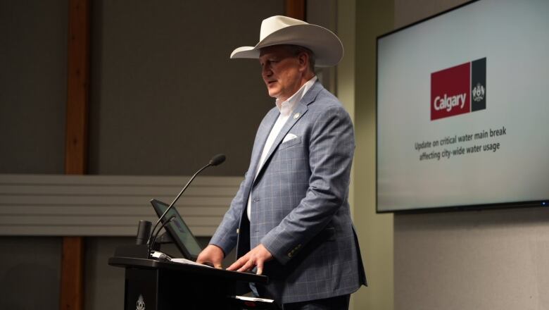 a man in a cowboy hat speaks into a podium