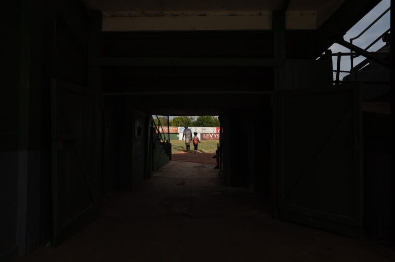 A man and a child walk on a baseball field.