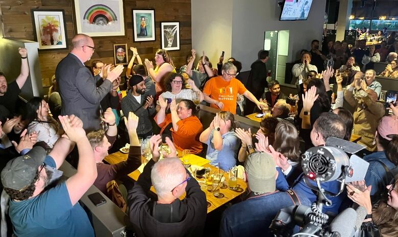 People gathered in a restaurant cheer.