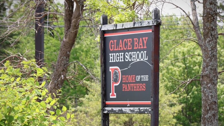 A wooden sign painted black and white and red labelled 