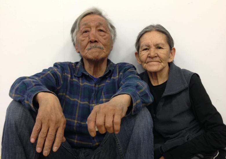 Two seniors sit on the floor. 