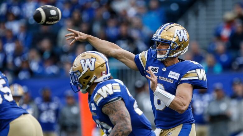 A quarterback in a blue uniform throws a football.