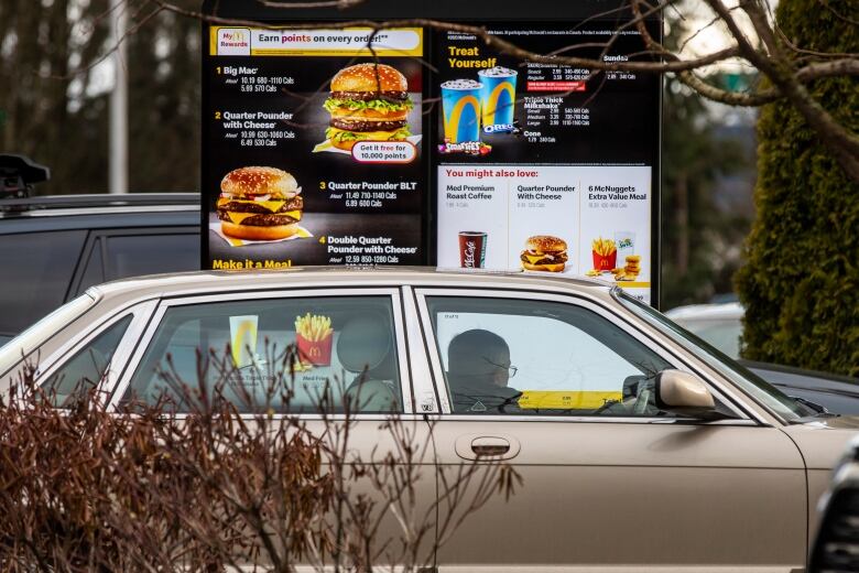 A car pulls up to a fast food drive-through window.