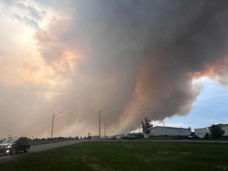 Orange smoke from wildfire takes over community with blue skies.