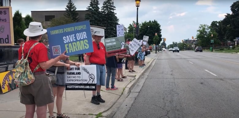 People with sign protesting along a street. 