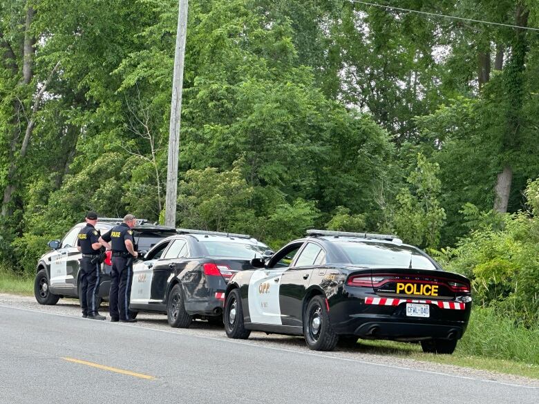 Three police cars on the side of the road