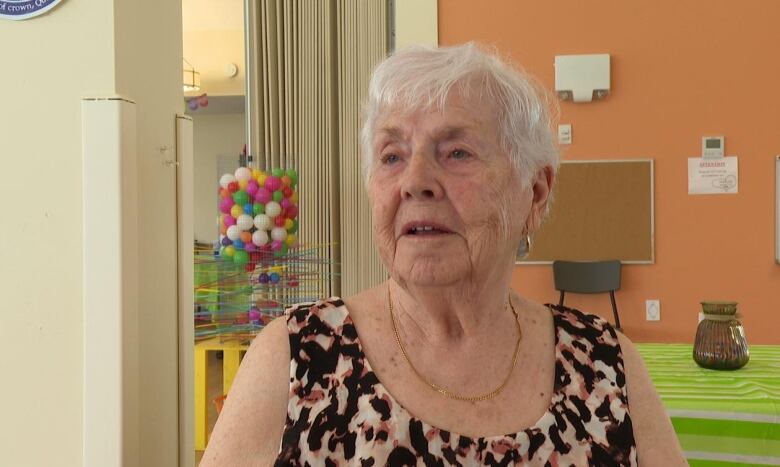 A woman with short white hair and a tank top.