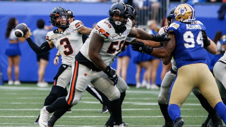 A quarterback in white rears back to throw the football.