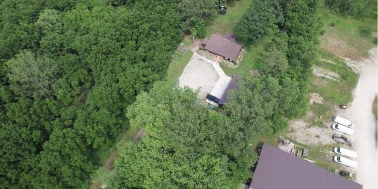 Overhead shot of a home surrounded by trees and with a large parking area