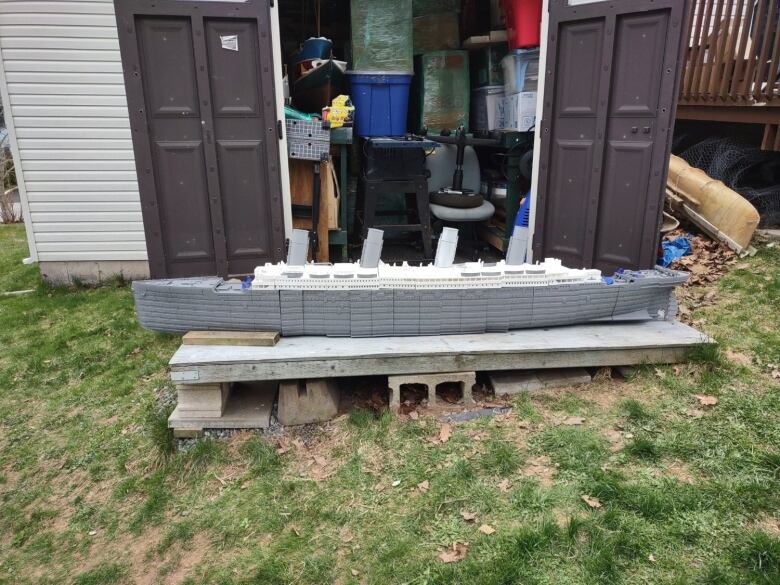 A plastic model of the Titanic in progress  is seen sitting outside a garden workshop.