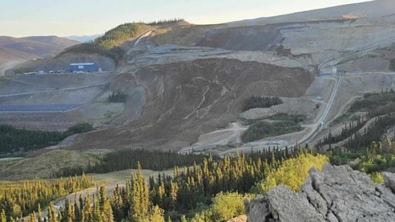 A landslide area is visible from afar at a remote mine site.