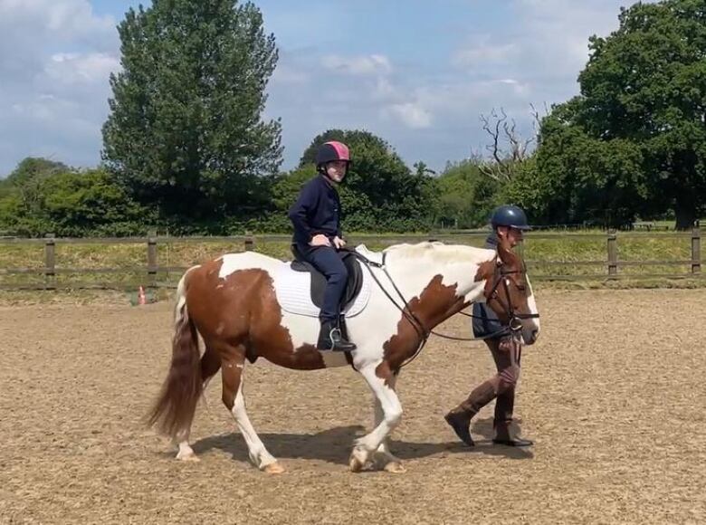 A man leads a horse with a smiling boy on its back. 