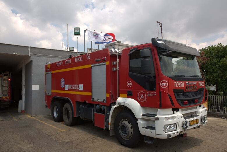 A red fire truck is parked outside a fire station. 