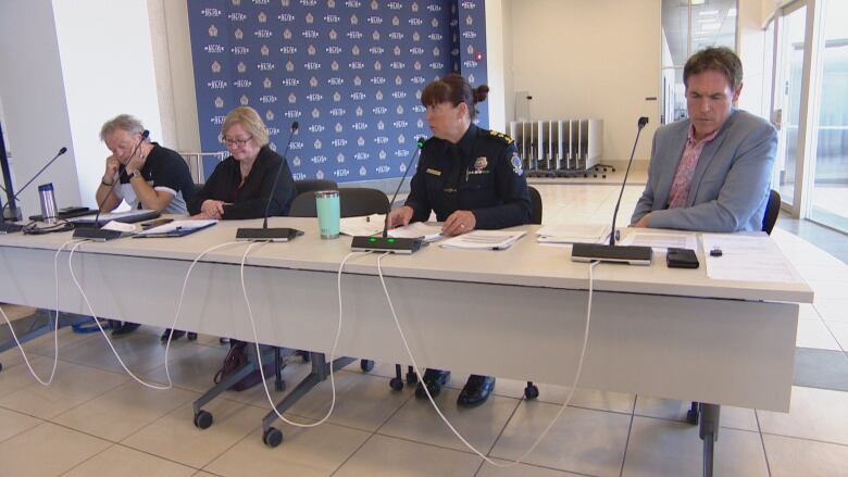 four people sit at a table to go over a report with the board.