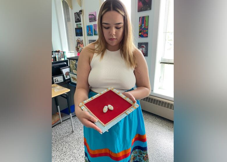 A woman holds a beaded grad cap. 