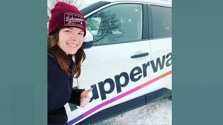 A woman with a vehicle bearing a Tupperware logo.