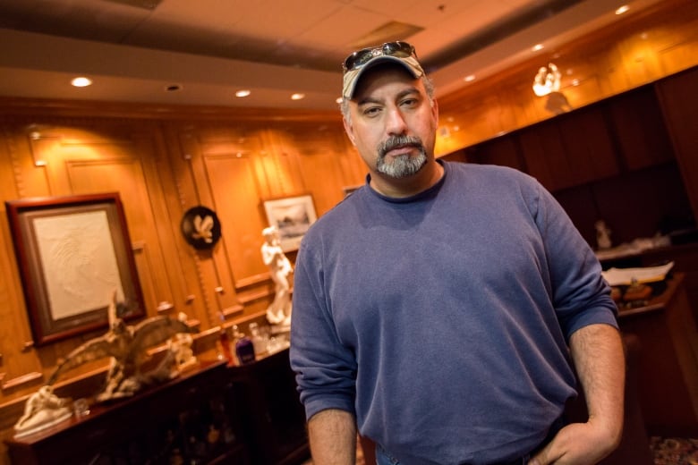 Man in a baseball hat standing in a room.