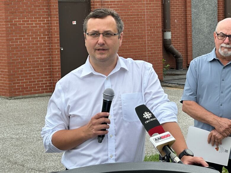 A man with glasses holding a microphone.