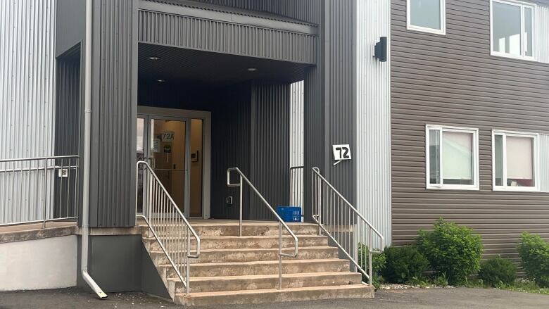 An apartment building with grey and taupe vinyl siding.