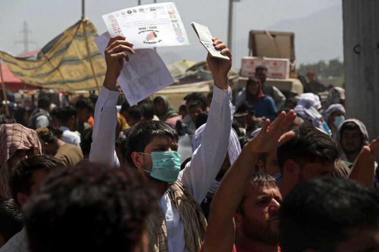 In this Aug. 26, 2021, file photo, hundreds of people gather, some holding documents, near an evacuation control checkpoint on the perimeter of the Hamid Karzai International Airport, in Kabul, Afghanistan. Many U.S. citizens and green card holders are still in the Afghan capital despite official promises that every American who wants to leave Afghanistan would be taken out.