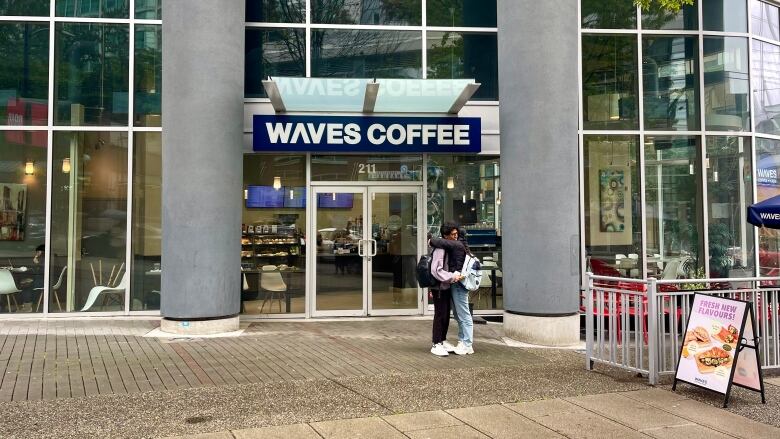 A long glass-fronted building framed by two concrete pillars framing a sign that says Waves Coffee.