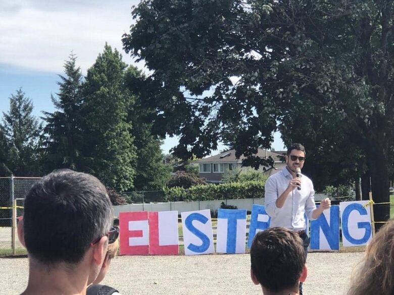 A man holds a mic at an outdoor rally.