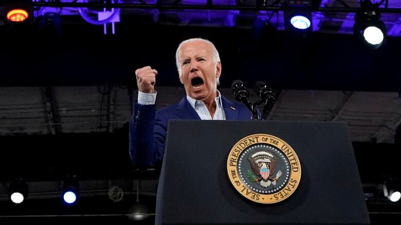 Biden speaking at lectern, pumping fist