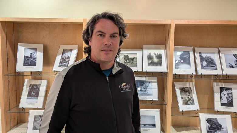 A man stands in front of a display of black and white photos 