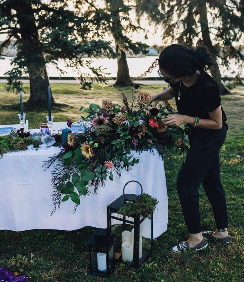 A woman arranging a bouquet of flowers outdoors.