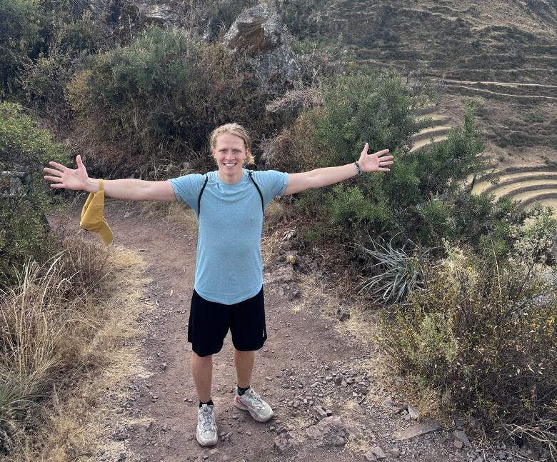 A man is pictured outside with his arms outstretched.