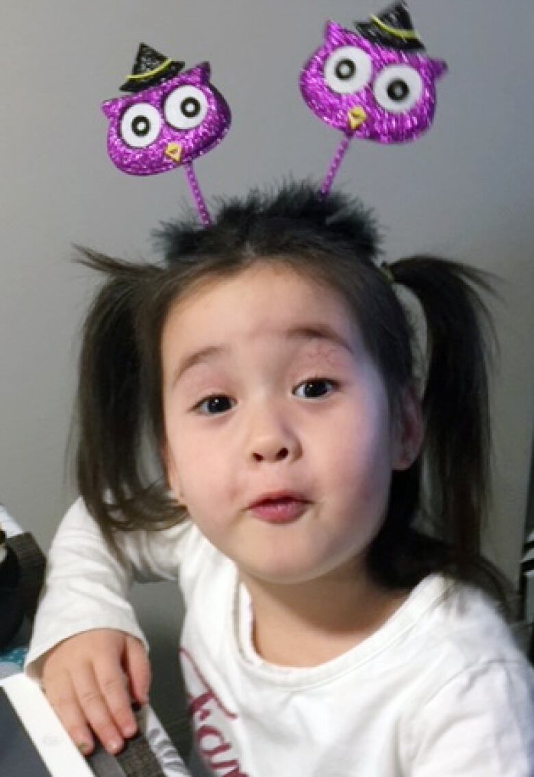 A young girl with a sparkly purple Halloween headband.