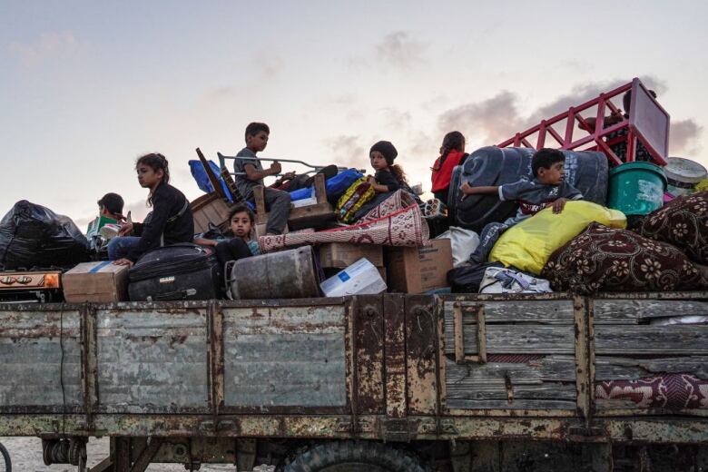 A group of children ride in a truck with their belongings.